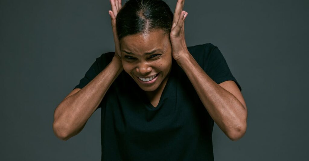 Portrait of an adult woman covering ears, looking irritated, against a dark background.