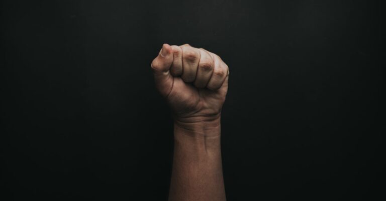 A powerful image of a raised fist against a dark background, symbolizing strength and unity.
