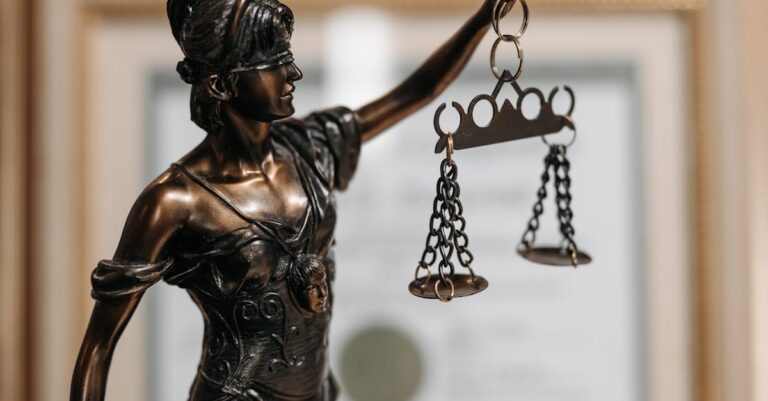 Close-up of a bronze Lady Justice statue holding scales in an office environment.