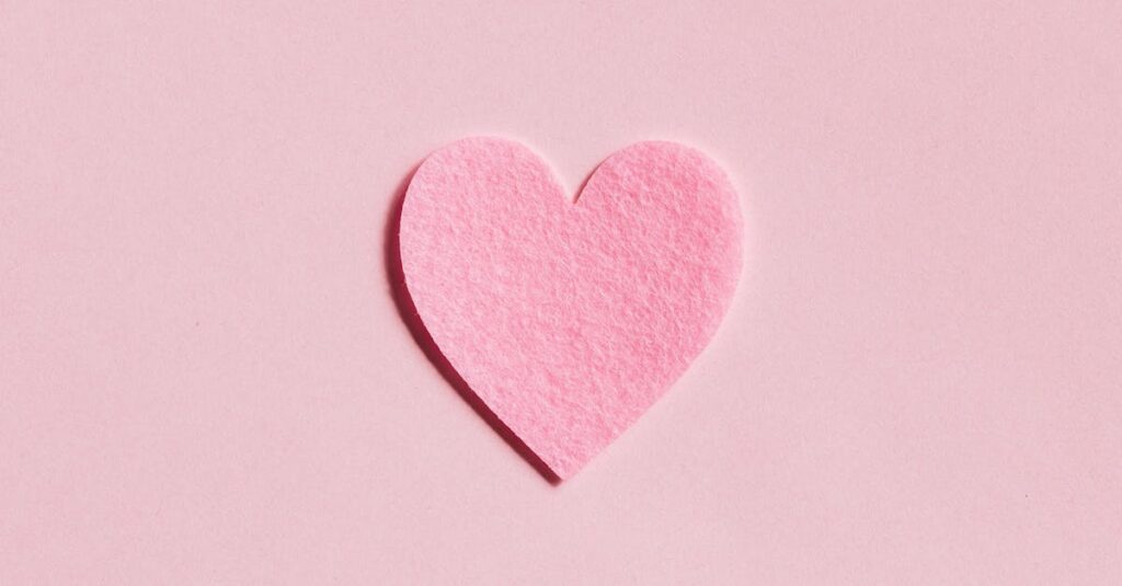 A simple pink felt heart on a light pink background, perfect for Valentine's Day themes.