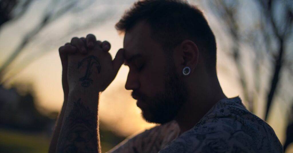 Profile of a tattooed man in serene contemplation at sunset.