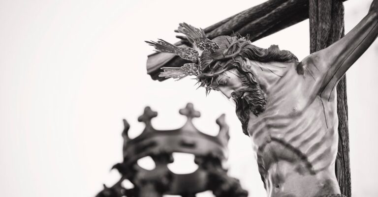 A dramatic close-up of a crucifix statue outdoors in Carmona, Spain, highlighting religious symbolism.